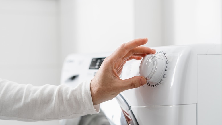 Hand turning washing machine dial
