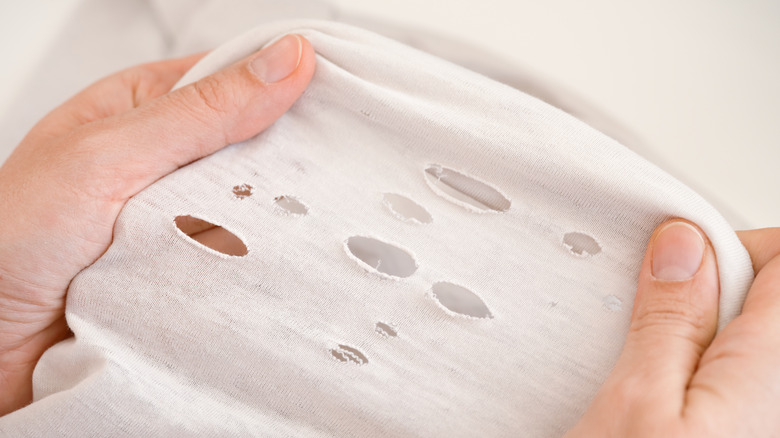 Woman holding holey shirt