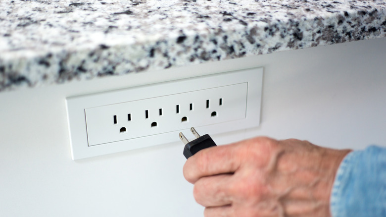 Hand plugging in U.S. appliance into U.S outlet