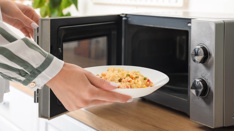 woman putting risotto in microwave 