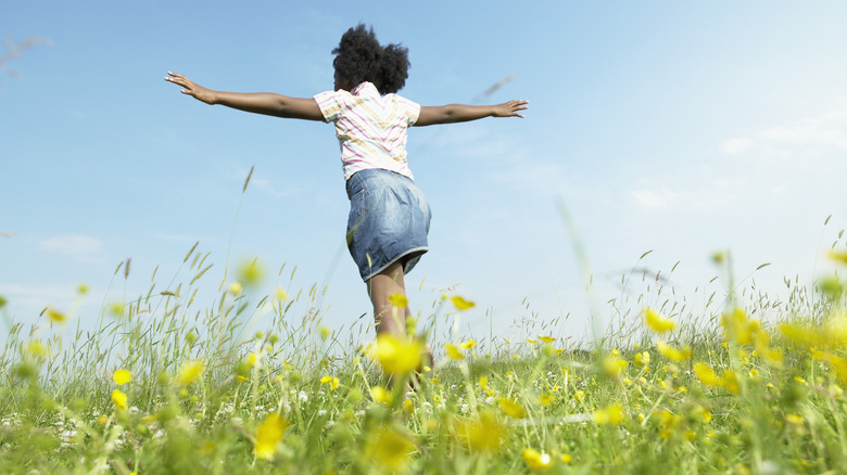 A girl walking through a field of flowers 