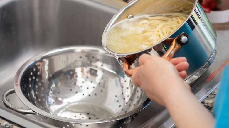 Person draining pasta into colander