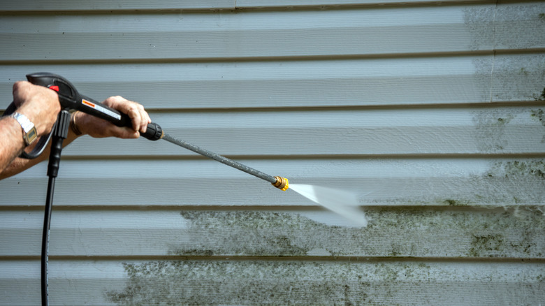 Person pressure washing house