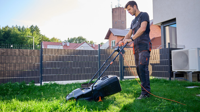 man in backyard with electric lawn mower