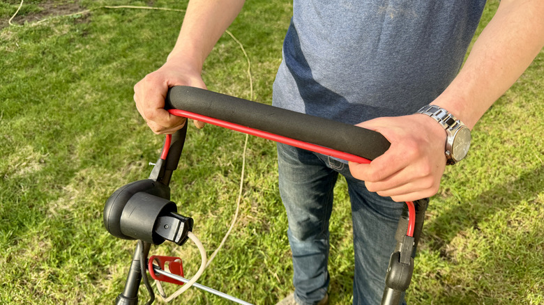 person holding lawn mower handle