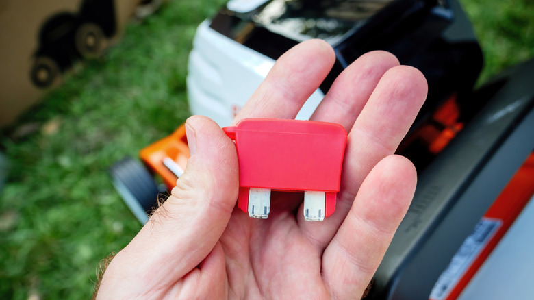person holding red lawn mower safety key