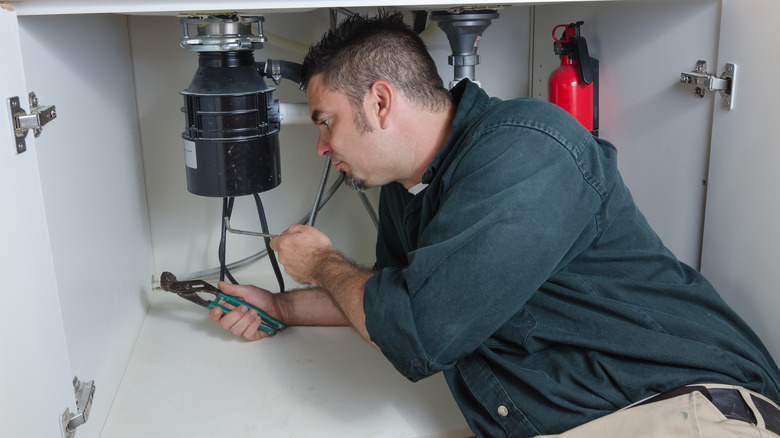 Man repairs garbage disposal