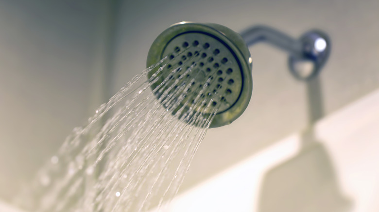 A silver shower head with water flowing out of it