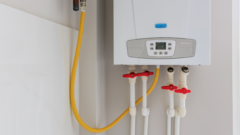 Modern tankless gas water heater with yellow gas line in utility room
