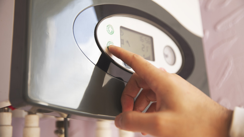A hand pressing a button on an automatic heating system