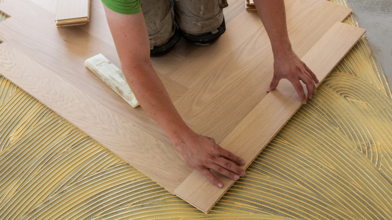 A person laying herringbone flooring
