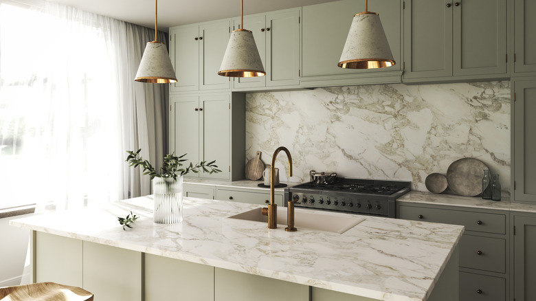 Neutral green kitchen with matching marble backsplash and countertop