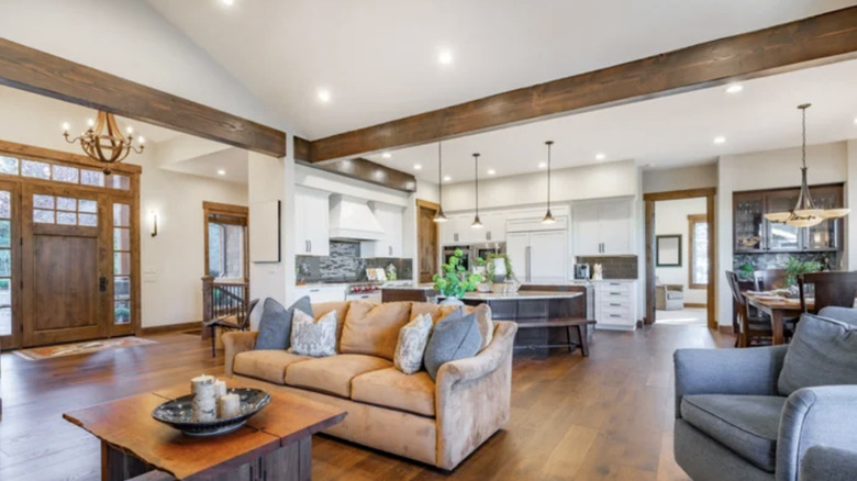 Living room with white walls and wooden beams on ceiling.