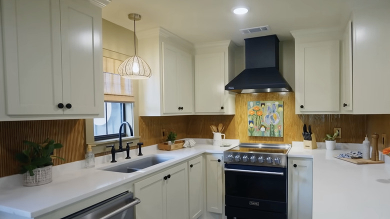 Cozy kitchen with white cabinetry and fluted wood backsplash.