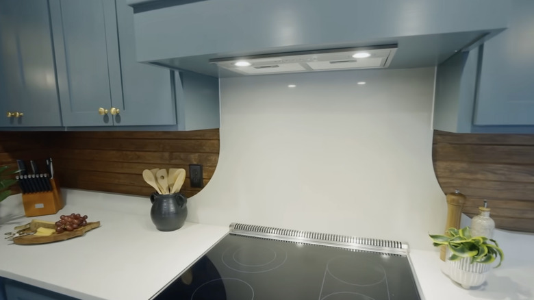 White countertop extending up to oven hood and surrounded by wood slat backsplash.