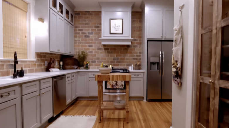 Kitchen with high ceilings, wood floors, and a brick backsplash.