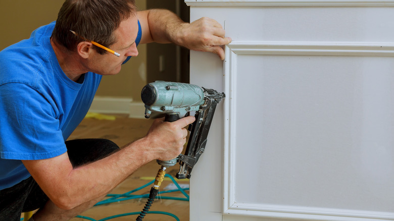 man installing picture moulding to wall