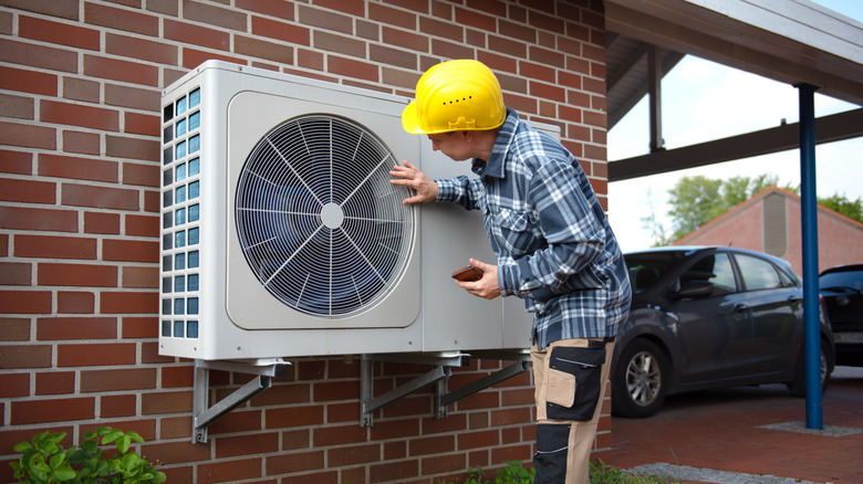 Man installing a heat pump at a home