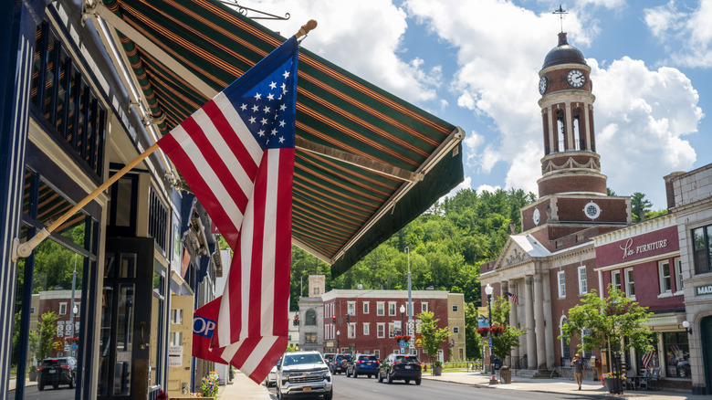 An American flag in the foreground of a small town.