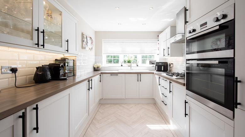 All-white kitchen with wood counters and black handles on cabinets