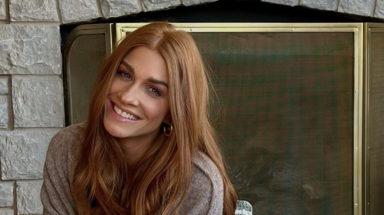 Jenn Todryk smiling in front of a fireplace