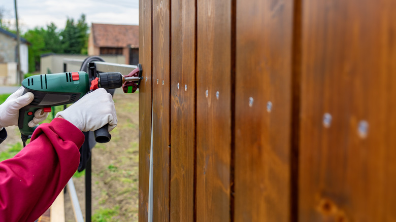 A person building a privacy fence