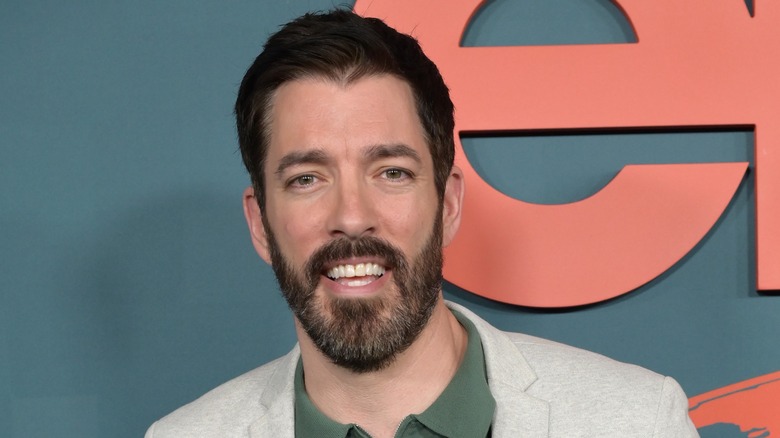 Bright bedroom with gold light fixture, dresser, and blue armchair