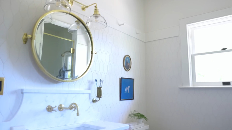 A round gold mirror with white tile.