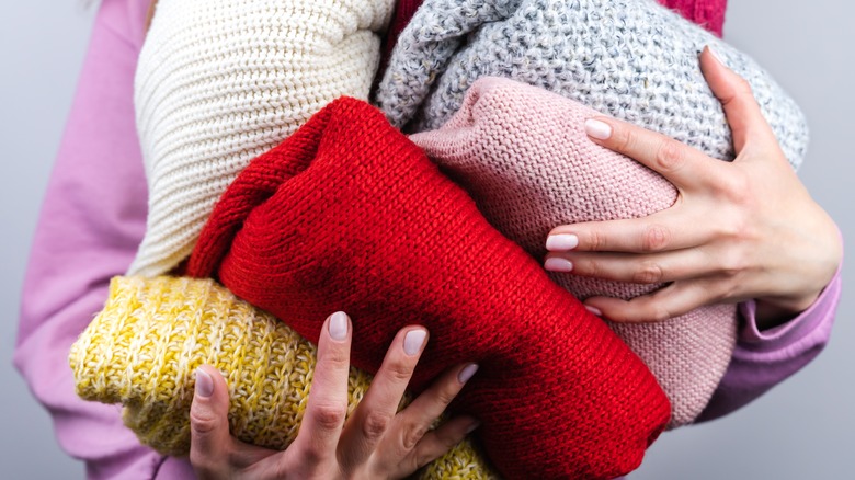 woman holding many sweaters