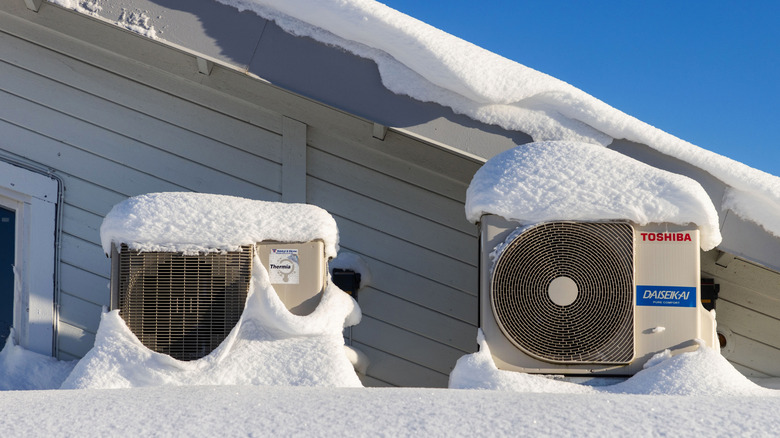 Two heat pumps are covered by a thick layer of snow