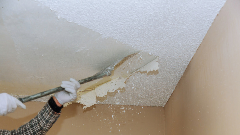 cropped image of hands scraping a popcorn ceiling