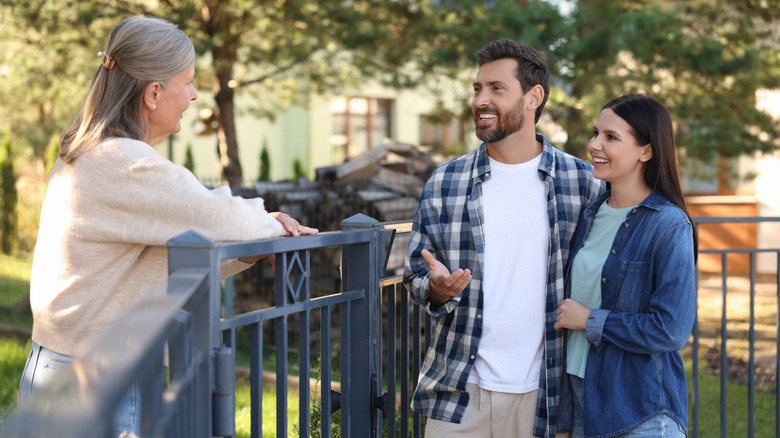 Three people standing around a fence talking and smiling