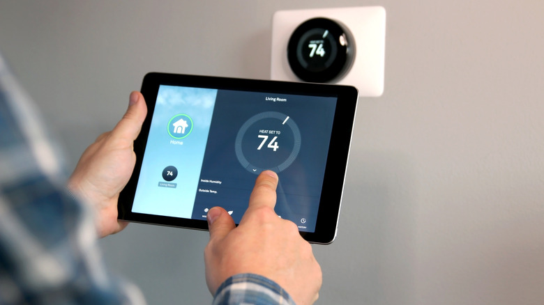 A person with a blue flannel shirt adjusting their smart thermometer on a tablet