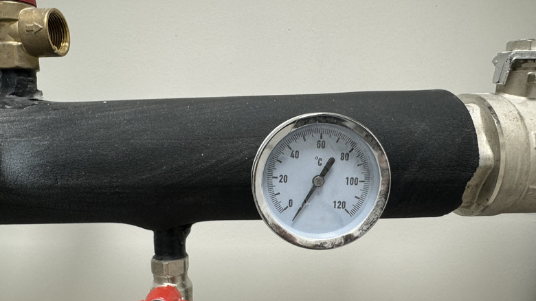 A pipe wrapped in black insulation with a temperature gauge in the front