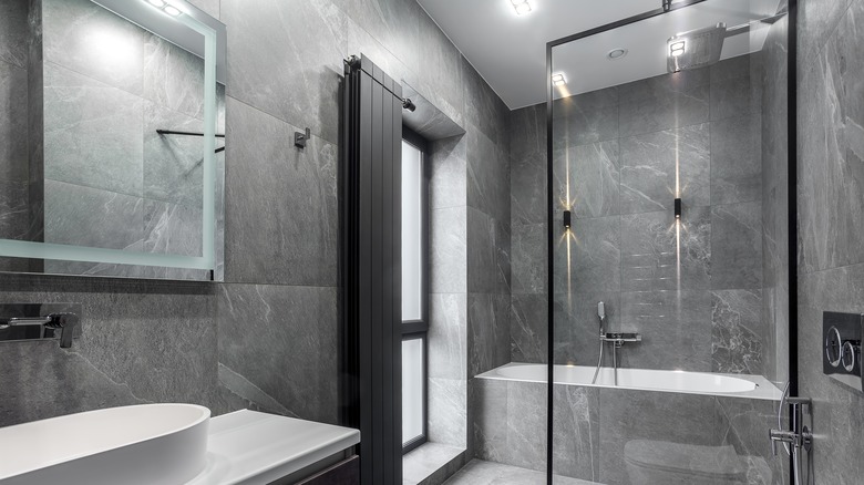 Dark colored stone on wall of a glass shower in a luxury bathroom.