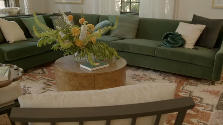 A large green sectional and aztec area rug.