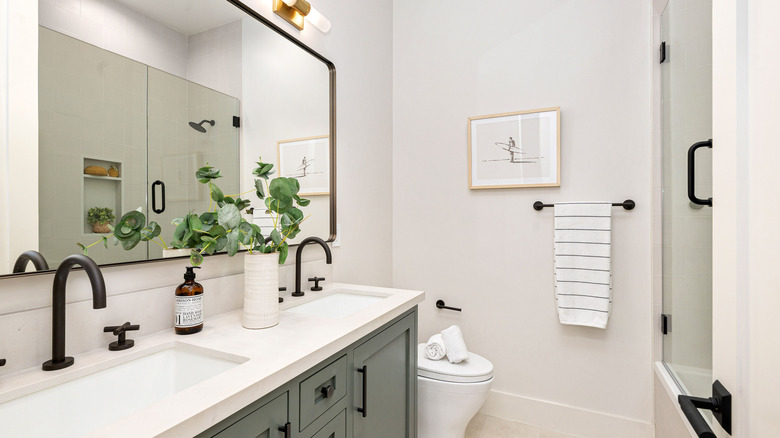 A modern bathroom design with a large mirror and two sinks in the vanity.
