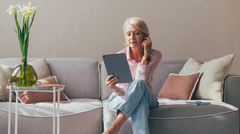woman looking at tablet while sitting on boneless sofa chaise