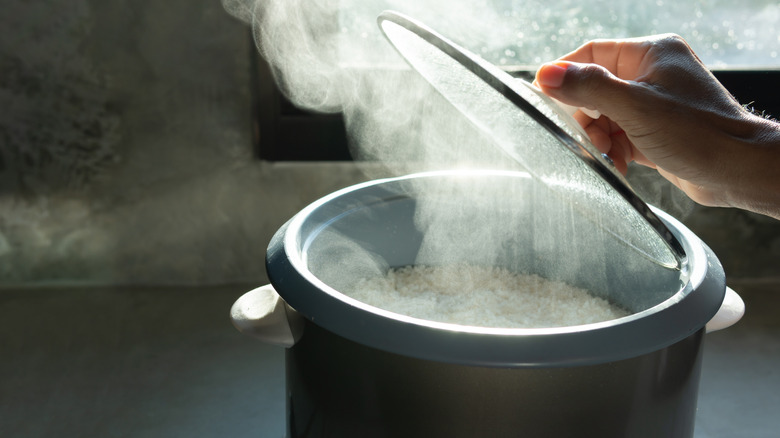 person uncovering rice cooker