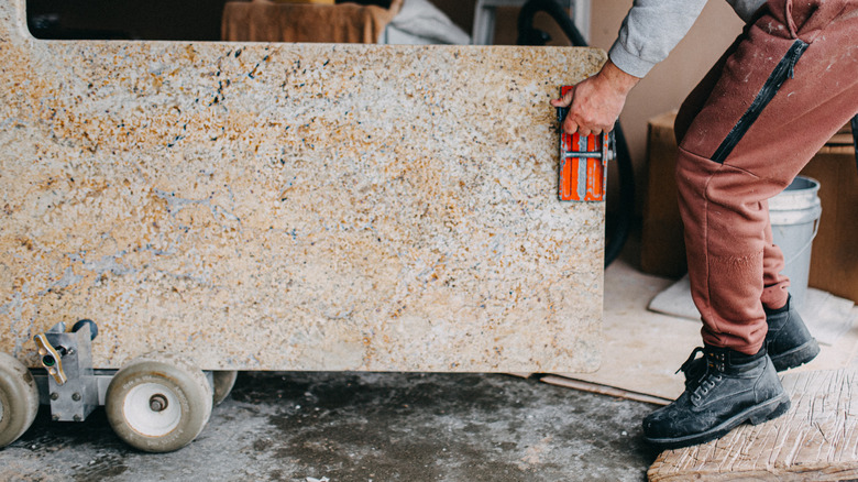 A construction worker moving a slab of granite