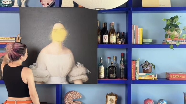 A person slides a picture to reveal a hidden bar on an Ikea bookshelf