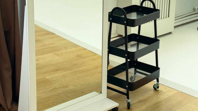 Black utility cart next to a mirror.