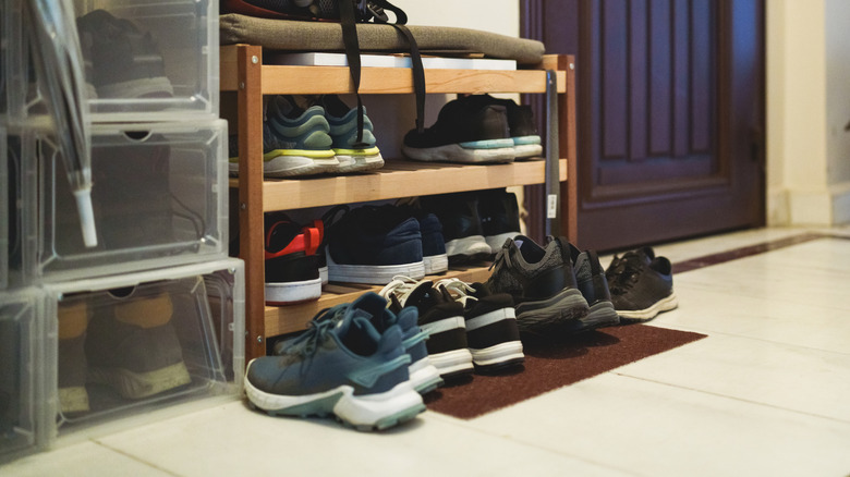 A shoe rack with shoes on it and in front of it.