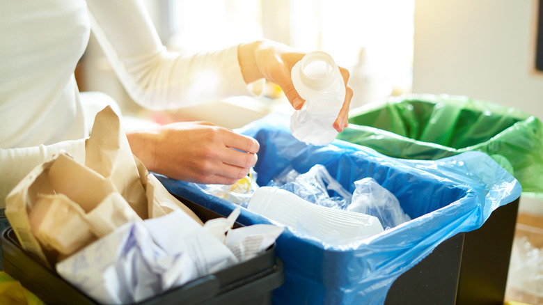 Woman separating trash into three different open-top bins