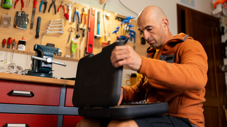 A man sorting through tools in a carefully organized home workshop
