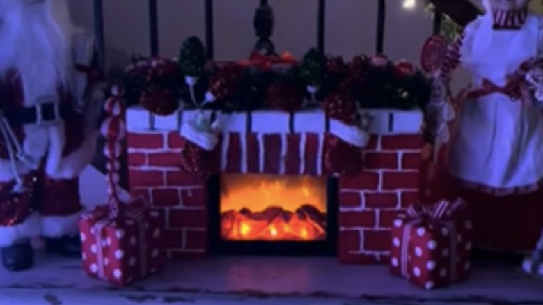 Dollar Tree Christmas flame lantern sits in a faux fireplace surround decorated for the holidays