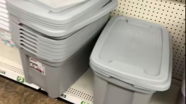 A stack of gray plastic bins with lids on a shelf at Dollar Tree