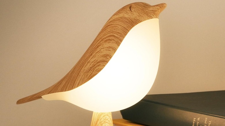 The Deogos Small Bird Desk Lamp illuminated near books