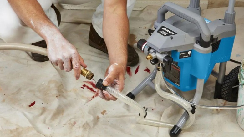Person's hands connecting hose on the Avanti's Airless Paint, Primer, and Stain Sprayer