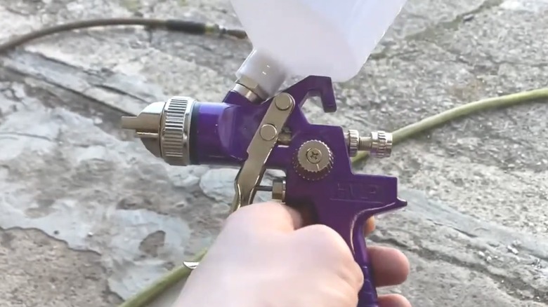 Man holding a Central Pneumatic's 20-ounce HVLP Gravity-Feed Air Spray Gun With Regulator